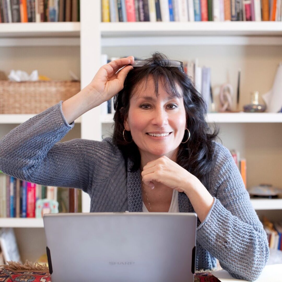 A woman sitting at a table with her laptop.